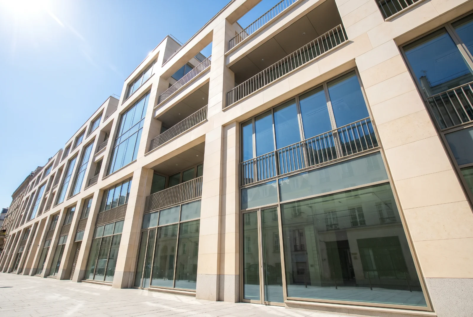 Immeuble de bureaux moderne en pierre claire et verre sous un ciel bleu